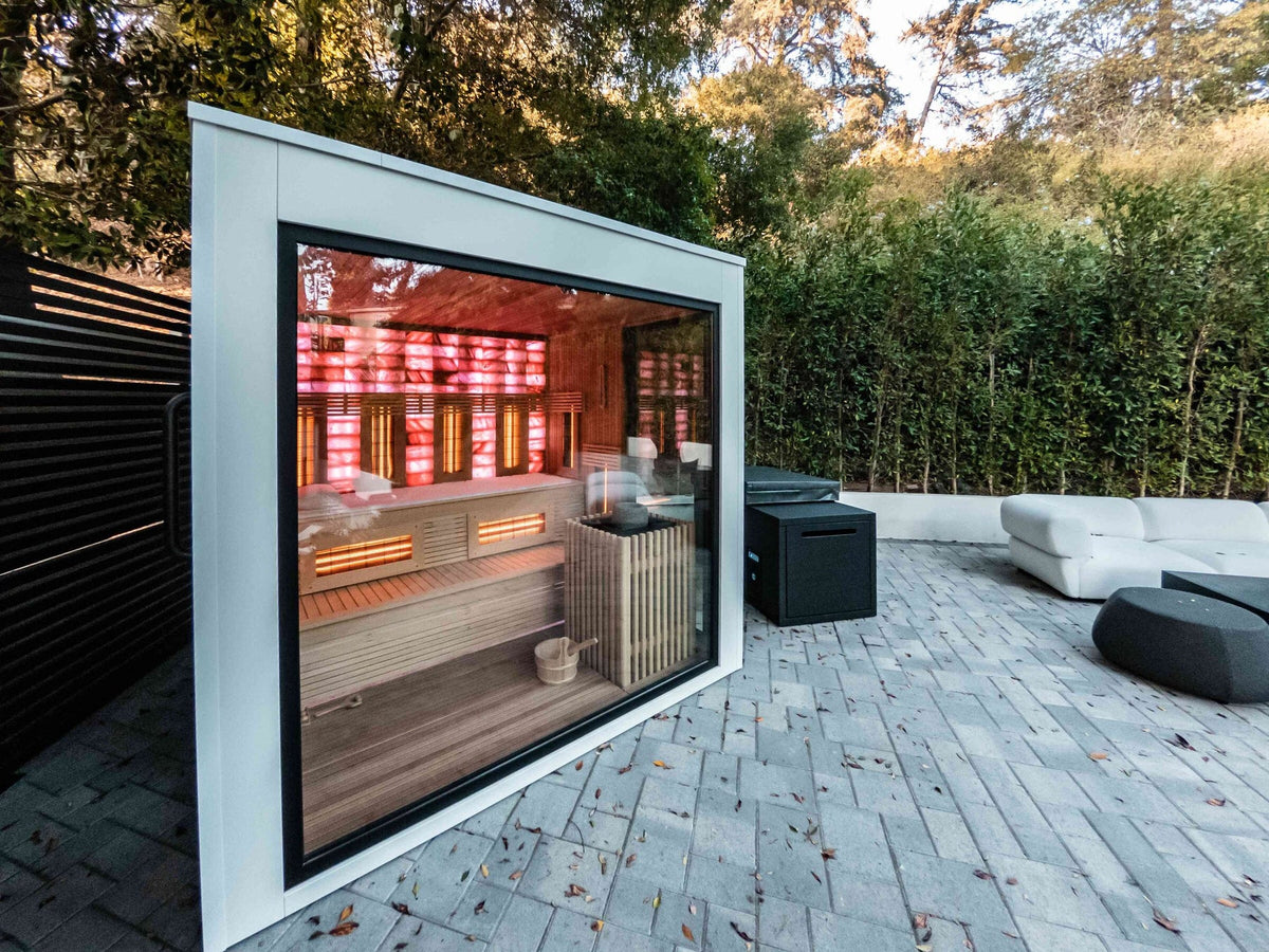 Modern glass infrared sauna glowing with red infrared panels on a patio